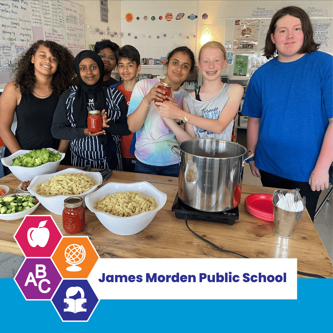 Classmates at James Morden Elementary School in front of a table with food