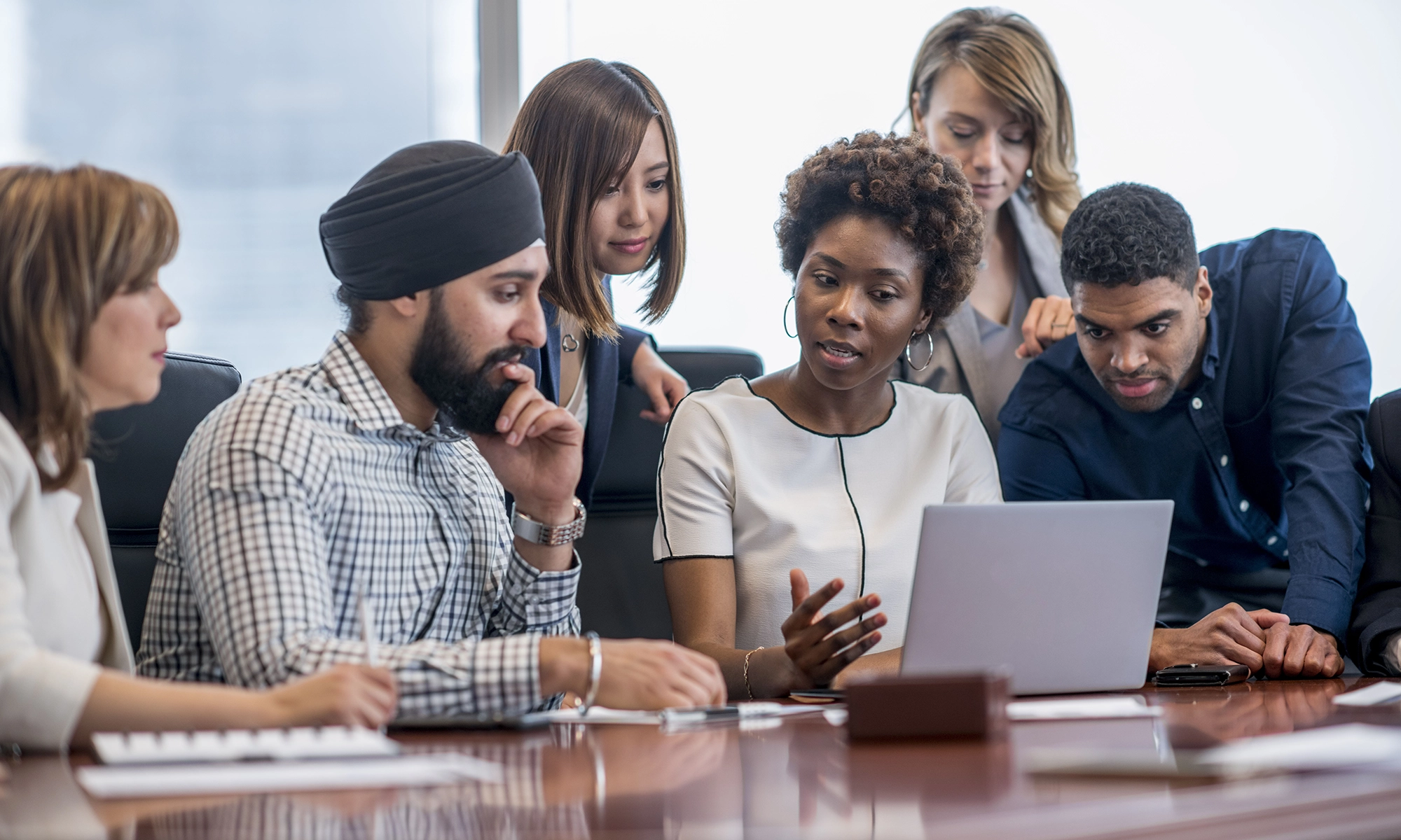 Group of business people look together at a laptop.