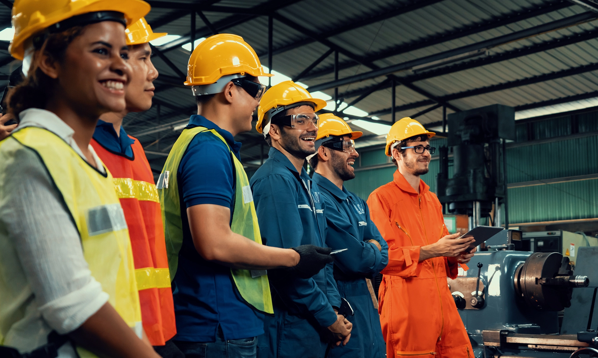 Line up of workers wearing safety equipment in a factory.