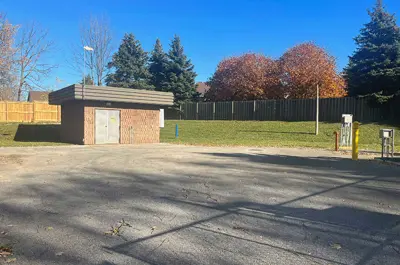 The Laurie Avenue Sewage Pumping Station is a small red brick building surrounded by a paved walkway by a grassy area