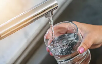 Hand holding glass under tap and filling with water