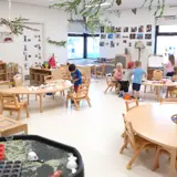 Children in a child care centre with tables, chairs, toys and crafts