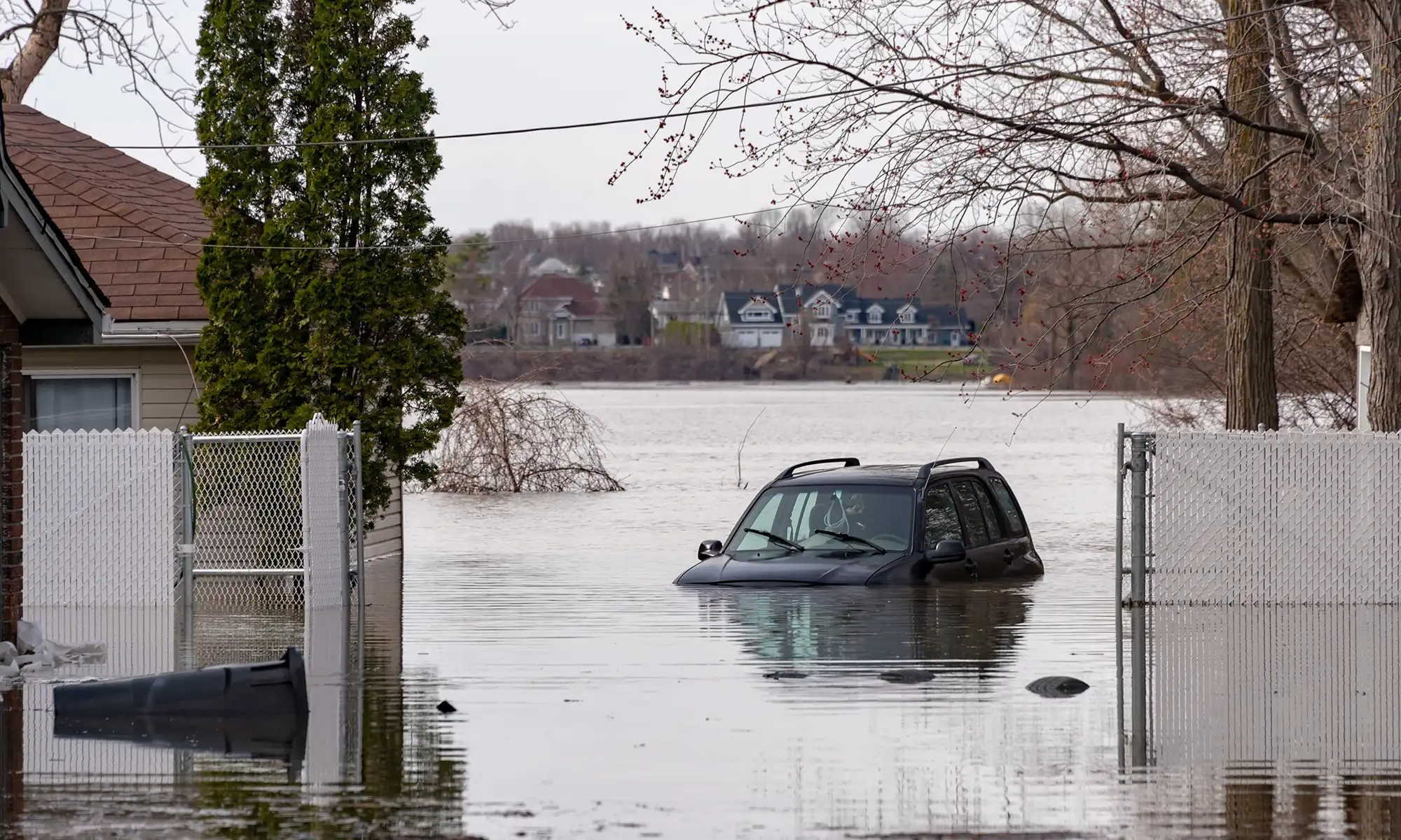 A car partially underwater in a neighbourhood due to flooding.