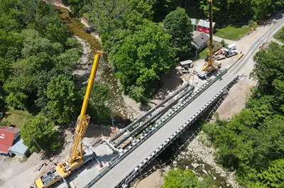 An overhead view of bridge construction. A crane is working on the bridge area