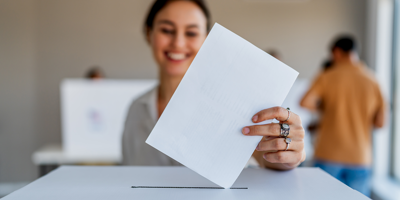A woman putting her voting ballot in a box