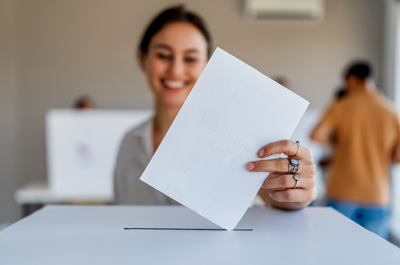 A woman putting her voting ballot in a box