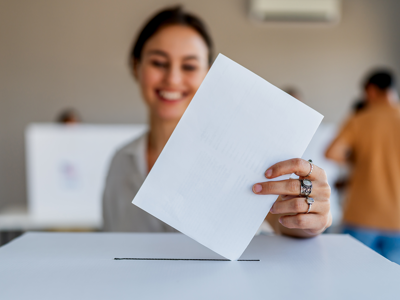 A woman putting her voting ballot in a box