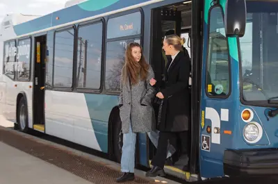 People stepping off a transit bus onto a sidewalk