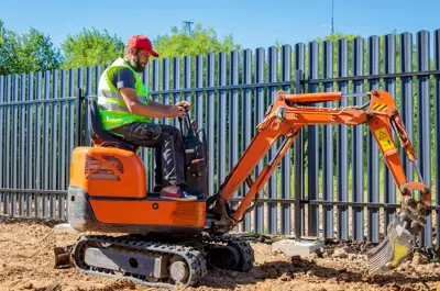 Man working on a mini excavator loosening soil