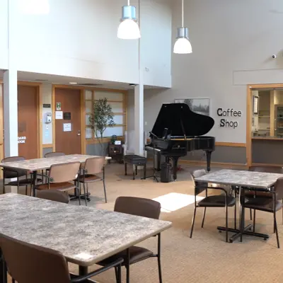 A recreation area at Rapelje Lodge with tables, chairs, and a grand piano