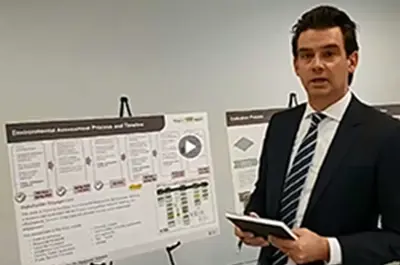 Chris Hamel stands next to an information board and looks into the camera