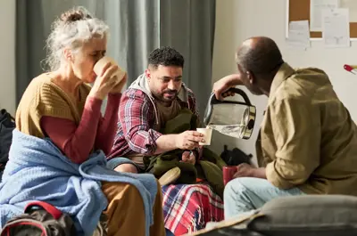 Diverse group of adults sharing hot drinks in emergency shelter