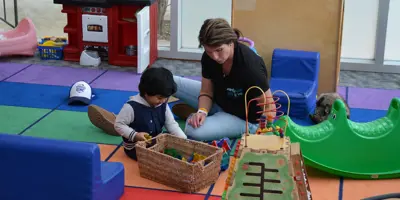 EarlyON child care worker playing blocks with a young boy