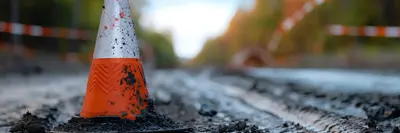 Traffic cone on a muddy road with caution tape