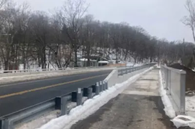 The completed bridge is partially covered in snow on an overcast winter day