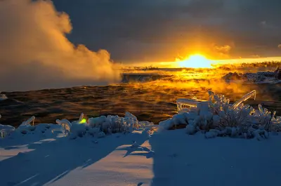 Niagara Falls at sunrise in winter. The sun is emerging over the horizons while cold air ascends from the falls.