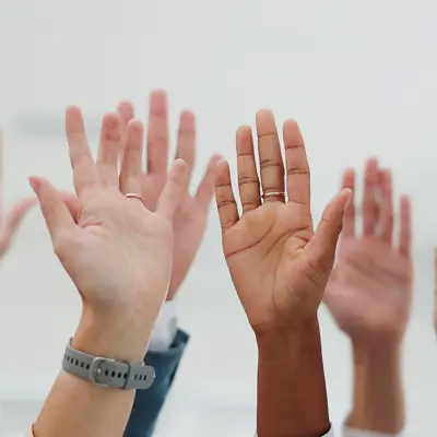 Multi racial hands raised to indicate they want to be heard.