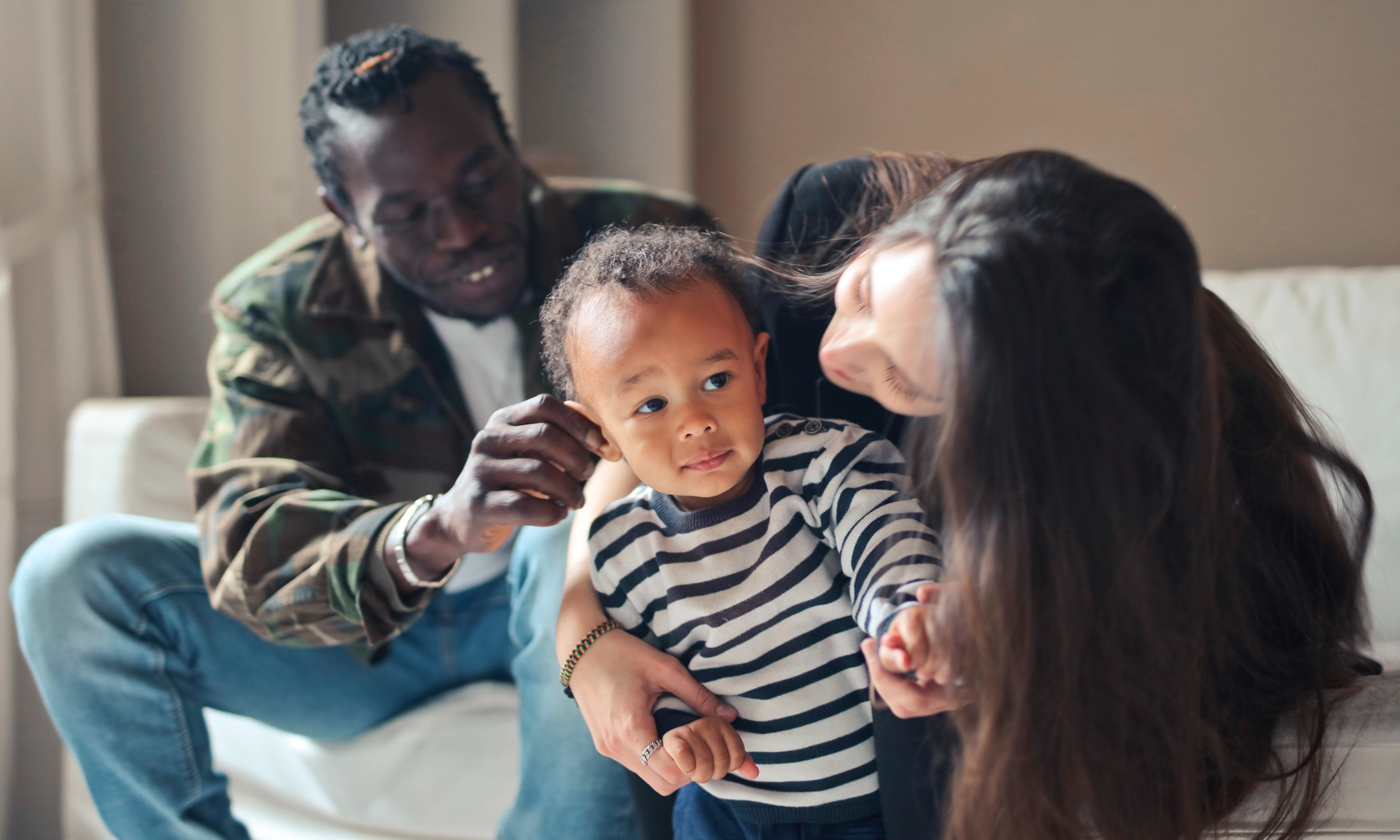 Multi-racial couple with their young child sitting on a couch