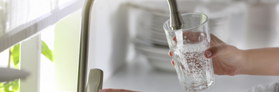 Close up of two hands filling a glass with tap water.