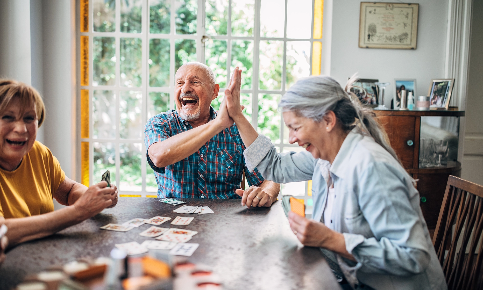 Older adults playing cards and giving a high five