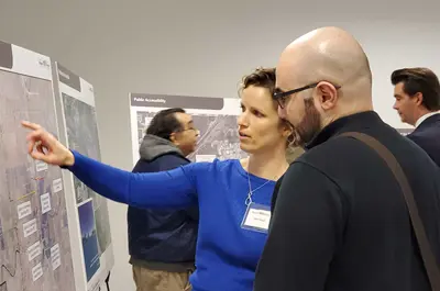 A woman points to a map on an information board while a man listens